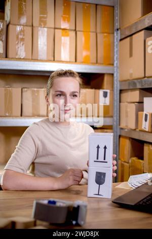 Woman prepares a product box for delivery to a customer. The box with the sticker is fragile. Online business, e-commerce and shipping concept Stock Photo