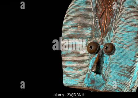 Close up of a wooden Kota reliquary figure from Gabon, isolated on a black background. Tribal African art, showcasing masterful craftsmanship and spir Stock Photo