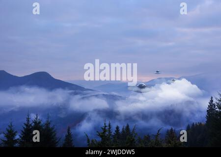 Alien spaceships flying in misty mountains. UFO Stock Photo