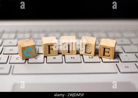 E file text on wooden blocks, Concept of tax filing through e file. On a computer keyboard. Stock Photo