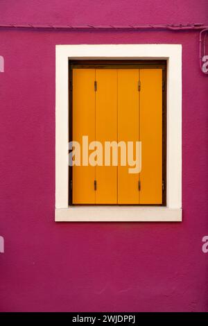 Front view of a Venetian building facade windows with wooden shutters and painted walls. Stock Photo