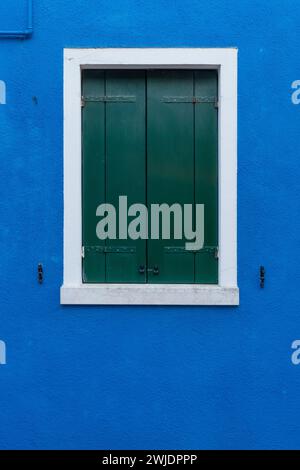 Front view of a Venetian building facade windows with wooden shutters and painted walls. Stock Photo