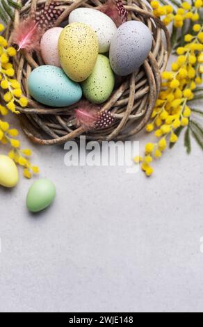 A close-up view of pastel-colored Easter eggs in a small basket, decorated with yellow spring flowers, symbolizing Easter celebration. Stock Photo