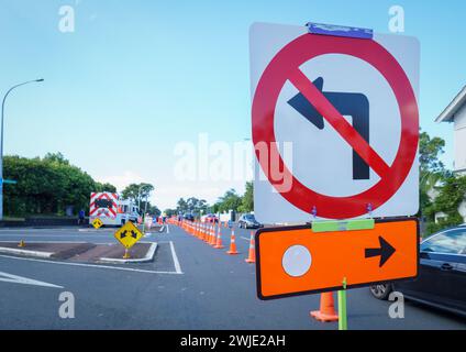 Detour road signs and orange traffic cones on the street. Cars driving on the restricted road. Roadworks in Auckland. Stock Photo