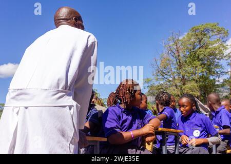A dedicated teacher and uniformed students engaged in an open-air classroom lecture Stock Photo