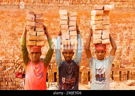 Dhaka, Dhaka, Bangladesh. 15th Feb, 2024. Workers carry piles of bricks weighing more than 20 kg on their heads in a kiln in Dhaka, Bangladesh. The labourers ''“ who are paid less than Â£1 a shift ''“ move up to 2,500 bricks a day in sweltering conditions. Around 4, 00,000 low-income migrants arrive in Dhaka from different parts of the country every year to work at brickfields. Long working hours under the scorching sun in the brick fields, massive accumulation of dust, the risk of falling from the trucks and piles of bricks, and carrying excessive loads pose serious health hazards for the w Stock Photo