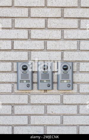 Three modern intercom on white wall near entrance to the house, space for text. Outdoor Video Intercom Door Station on brick wall. Intercom with video communication in the brick wall for opening door Stock Photo