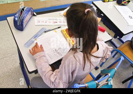Arvieux, Hautes-Alpes department (French Alps), Queyras: elementary school class. Schoolgirl sitting at her desk, writing in her mathematics workbook, Stock Photo