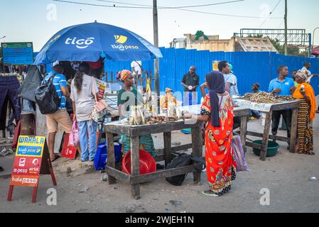 People sell fried fish to passengers passing through Kigamboni Ferry Terminal in Dar es Salaam, Tanzania Stock Photo