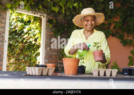 A mature biracial woman tends to plants in her home garden with copy space Stock Photo