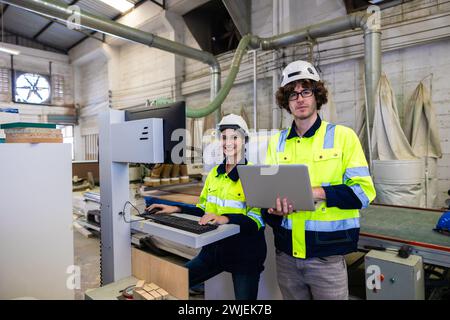 engineer team staff worker working in wooden furniture factory control operate wood cutter machine Stock Photo