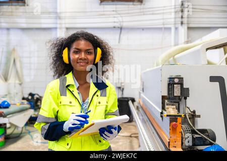 African black women worker work with wood cutter machine furniture factory industry with safety suit Stock Photo