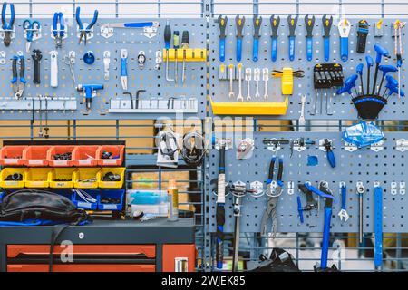 set of bike tools in bicycle professional service workshop for fix repair assembly set hanging on wall panel tool holder Stock Photo