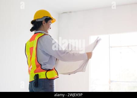 Smart young working women construction engineer builder caucasian female architect looking floor plan in under construction site building project mana Stock Photo