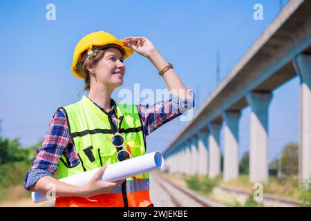 Portrait engineer women on railway tracks construction site with blueprint roll working project manager in suburb transportation line Stock Photo