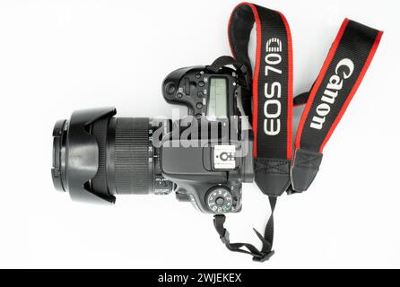 Valencia, Spain - August 8, 2021: Top view shot of a Canon 70D DSLR camera with 18-135 mm lens and its strap over white background. Product photograph Stock Photo