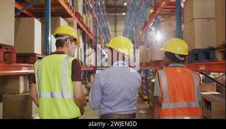 Diverse team of warehouse workers in discussion, with copy space Stock Photo