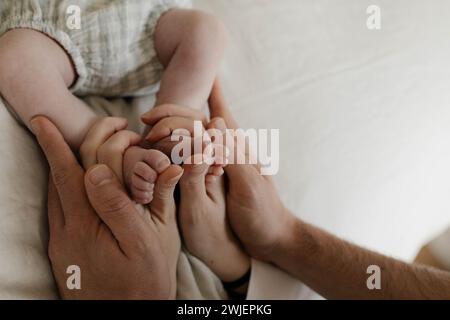 Newborn feet held by parents hands Stock Photo