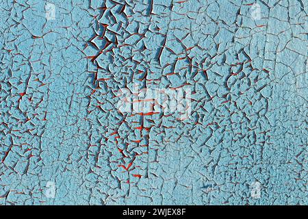 Texture of old blue cracked paint on red wall. Pattern of rustic blue grunge material. Stock Photo