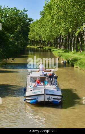 Couple on a rental barge on the Canal du Midi. Relaxing on the foredeck. The Canal du Midi is registered as a UNESCO World Heritage Site. Stock Photo