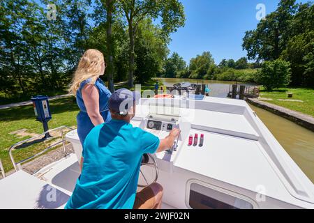 Young couple cruising on the Canal du Midi, passing through a lock. The Canal du Midi is registered as a UNESCO World Heritage Site. Stock Photo
