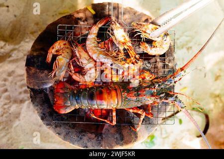 Seafood grill on the beach. Lobster, prawns and fish BBQ. Healthy lunch on summer sea vacation. Shellfish, squid and shrimp grilled on fire. Stock Photo