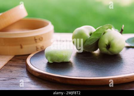 Three green apples displayed on a rustic wooden board.Mochi asian dessert Stock Photo