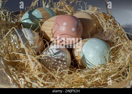 Multi-colored wooden Easter eggs lie in a paper nest Stock Photo