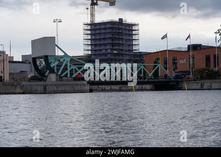 A metal bridge and a towering crane on the riverbank in Malmo, Sweden Stock Photo