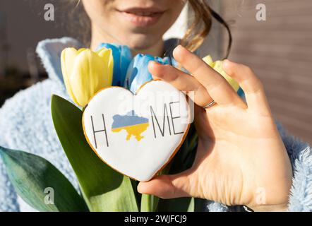 gingerbread in the shape of a heart with a map of Ukraine and the inscription Home in female hand. Peace to Ukraine. peaceful concept. Independence Da Stock Photo