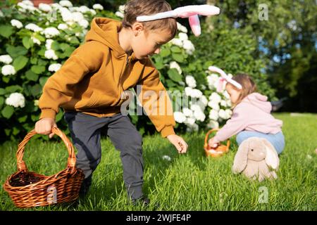 Cute boy and girl celebrating Easter, searching eggs. Happy kids laughing, smiling and having fun.  Stock Photo