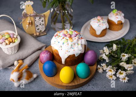 Easter kulich with candied fruits in white glaze with colorful sprinkles and painted eggs. Traditional Easter pastry. Easter holiday. Close-up, select Stock Photo