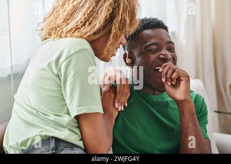 excited african american man in hearing aid device smiling happily near girlfriend at home Stock Photo