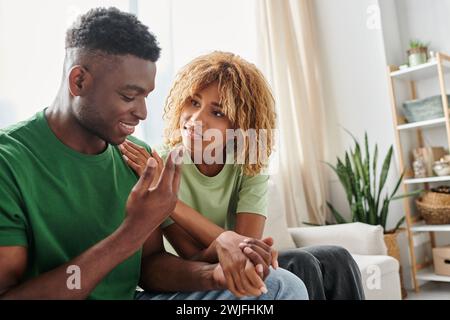 young african american couple holding hands while sitting together on sofa, emotional support Stock Photo