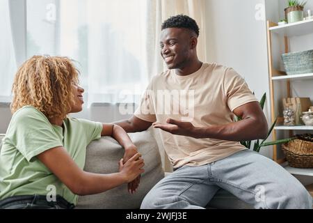 happy black man smiling while using sign language for communication with girlfriend in braces Stock Photo
