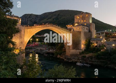 Old bridge over Neretva river in Mostar at dusk illuminated with lights Stock Photo
