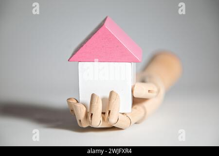 Model hand holding toy blocks in the shape of a hous, concept of real estate and house building Stock Photo