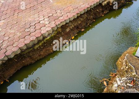 The erosion and reshaping of brick blocks along the edge of a residential water channel Stock Photo