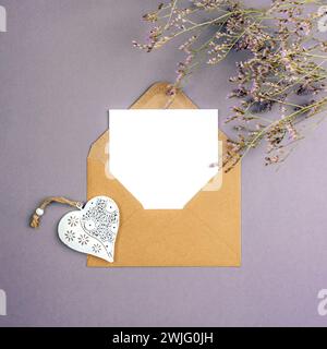 Envelope with blank card, vintage toy heart and flowers on gray background. Valentines day, womens day concept, top view, flat lay, mockup. Stock Photo