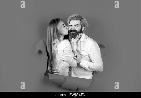 Couple through hole in blue paper, copy space for text or slogan. Discount and sale, people hole background. Surprised couple of bearded man and happy Stock Photo