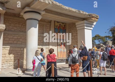 Palace of Minos, Knossos, Crete, Greece.  A group of tourists admiring the 'Procession' fresco in the South Propylaeum. Stock Photo