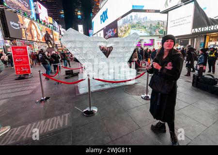 Tourists crowd Lovie Pignata’s “Smitten” ice sculpture, the winner of the Winter Ice Sculpture Show on Governor’s Island, in Times Square in New York on Valentine’s Day, Wednesday, February 14, 2024. The two mittens carved in ice forming a heart was upsized by the Okamoto Studio and will be displayed in Duffy Square until it “self-destructs” by melting. (© Richard B. Levine) Stock Photo