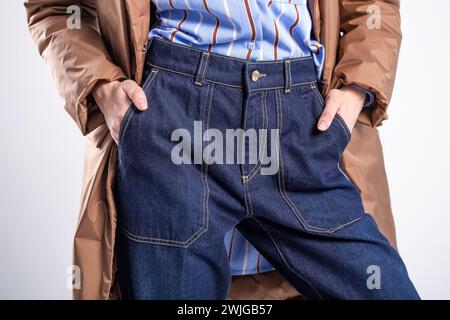 Close-up shot of a stylish woman in blue jeans, highlighting her hands in the pockets, ideal for showcasing urban streetwear fashion. Stock Photo
