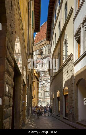 View of Santa Maria del Fiore, Duomo, Florence, Italy down a side street with reflection, tourist and cyclist Stock Photo