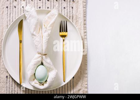Easter table setting with napkin in a shape of rabbit ears and blue egg, top view Stock Photo