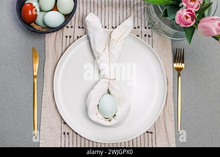 Easter table setting with napkin in a shape of rabbit ears and blue egg, top view Stock Photo
