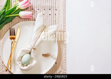 Table served for Easter, spring place setting with napkin in a shape of rabbit ears and blue egg Stock Photo