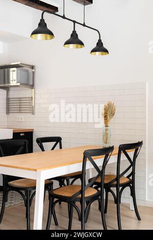 Fragment of a stylish living room with chairs and a dining table in a loft style with dark lamps in a modern apartment. Unique design concept for a Stock Photo