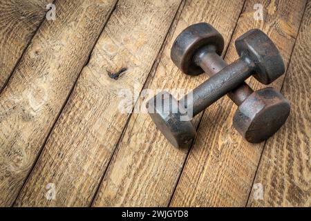 a pair of vintage iron rusty dumbbells on a grained barn wood background, fitness concept Stock Photo