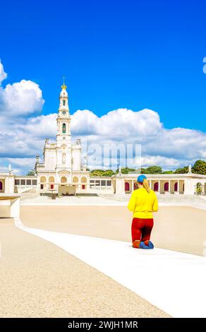 Portugal, Fatima Sanctuary - Devoted pilgrim woman walking alone on knees in the Penitential Path at Fátima marian shrine square. Stock Photo